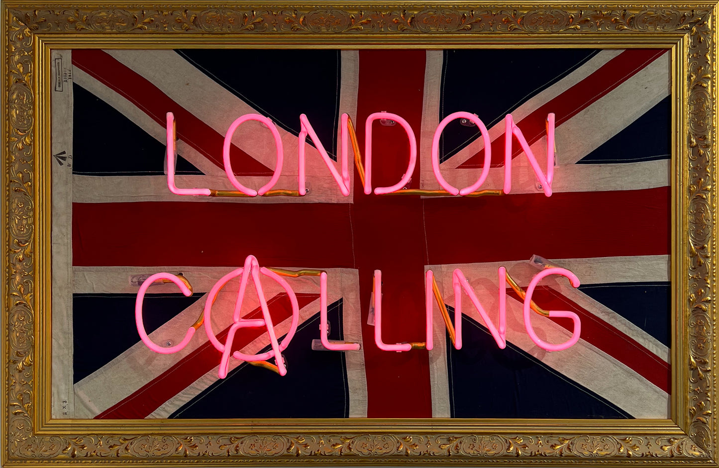 Mark Sloper "London Calling" original neon artwork shown unlit on an authentic vintage 1942 Union Jack flag. Hand-blown glass neon tubing mounted on a historical British flag, available at Creed Gallery Ascot.