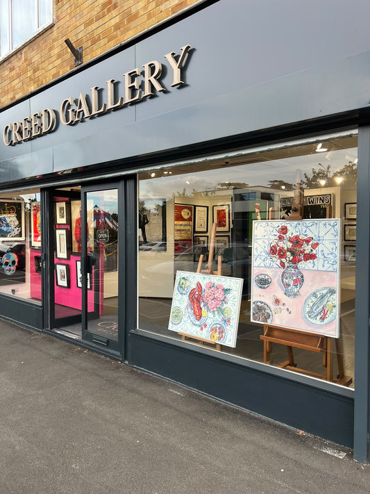 Creed Gallery shop window with two Pippa Smith still life paintings on easels, one with a lobster and one with poppies