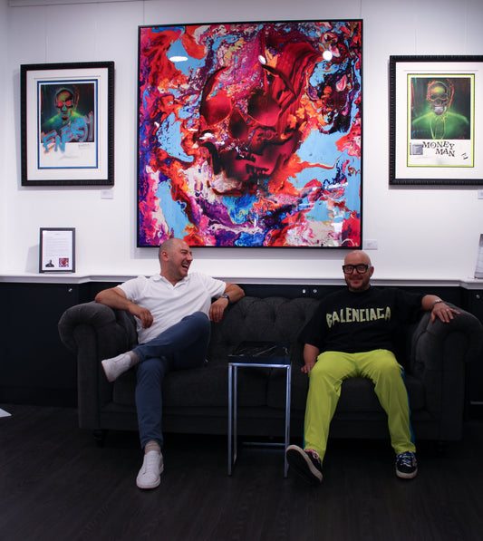 Interior of Creed Gallery featuring Lincoln Townley's 'Success' collection. A large, vibrant pink and blue skull painting hangs above two men on a Chesterfield sofa, flanked by 'Energy' and 'Money Man' prints.