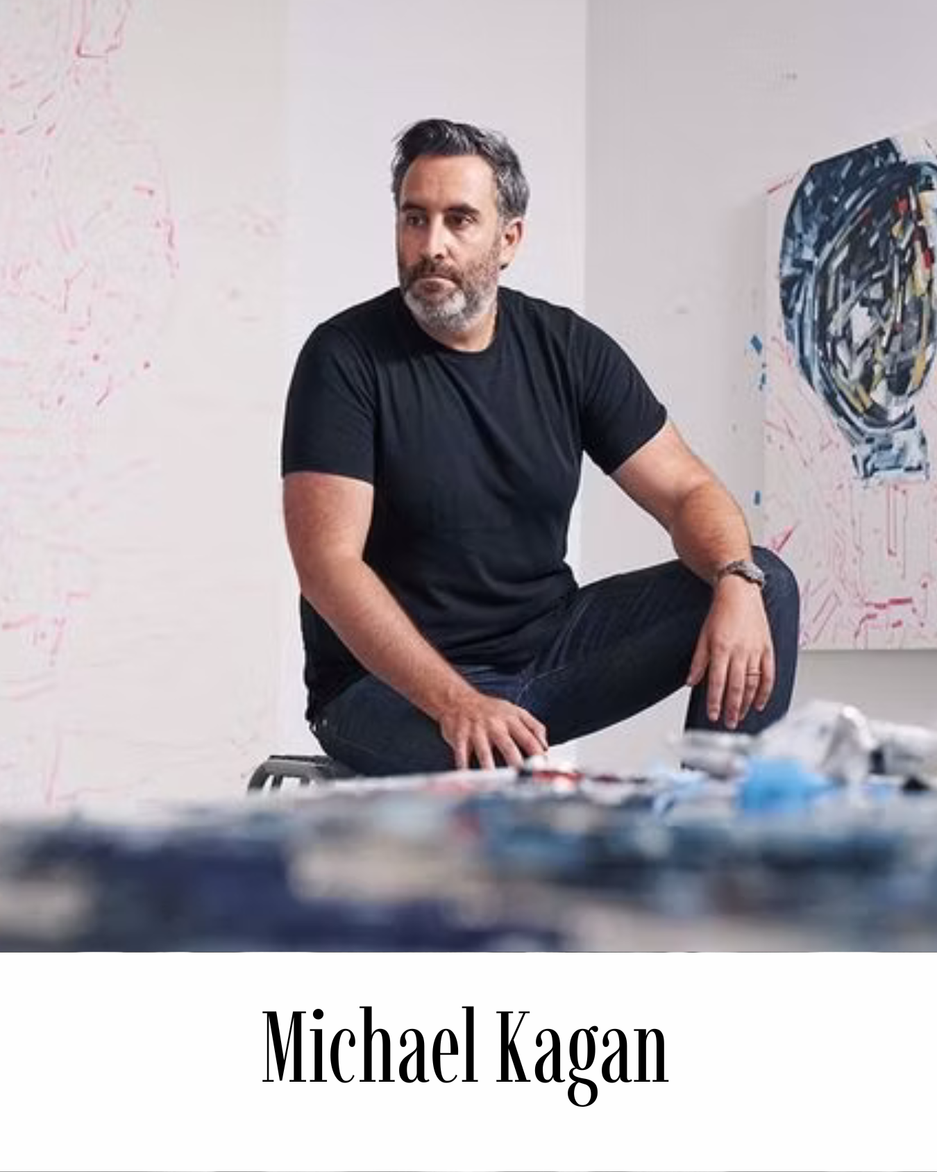 Michael Kagan photographed in his Brooklyn studio, seated in front of large-scale abstract paintings with characteristic gestural brushwork