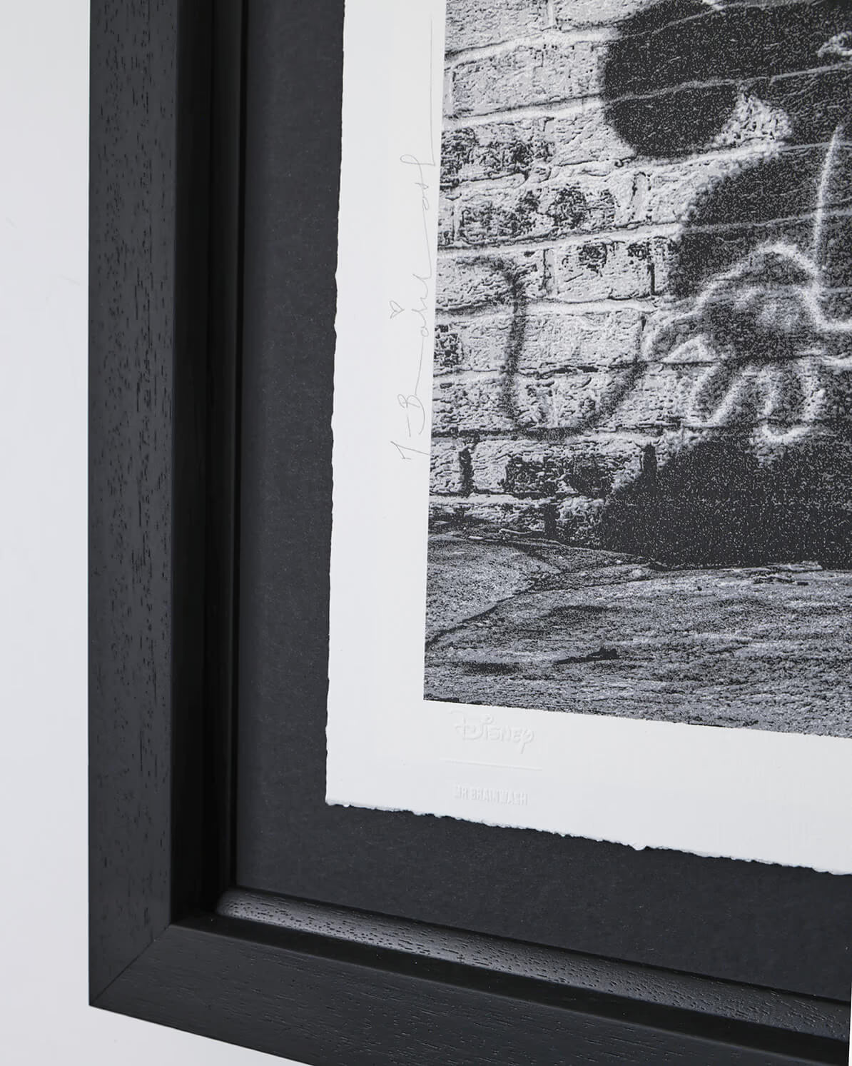 A side-angle view of the "Dreams Come True" signed limited edition print, highlighting the depth and finish of the black contemporary frame. This 27" x 27" (69 x 69 cm) framed piece showcases the high-quality mounting used for this Disney x Mr. Brainwash collection.