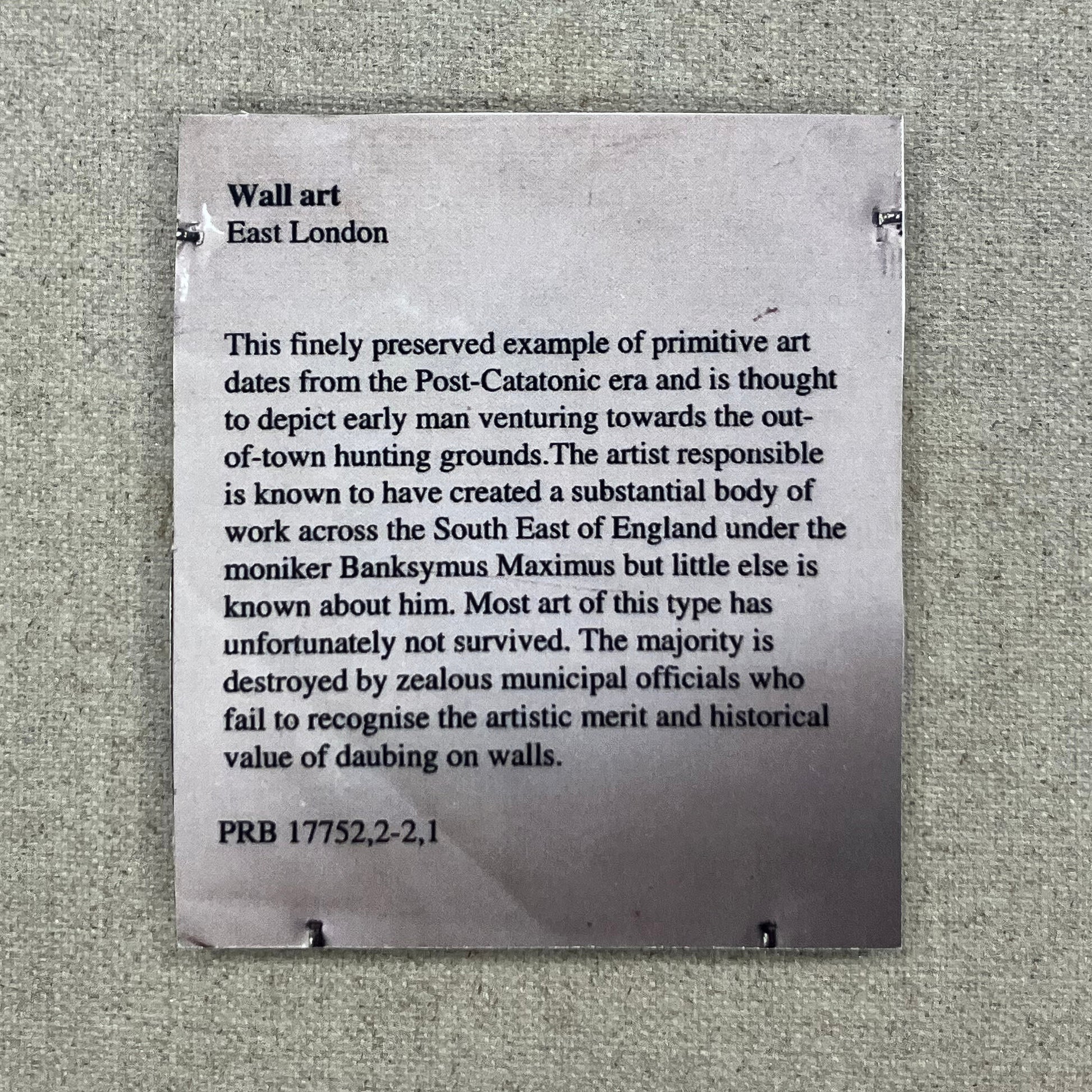 Reverse view of Banksy's 'Peckham Rock' showing the official British Museum information label and the satirical 'Post-Catatonic era' text, professionally framed and showcased at Creed Gallery.