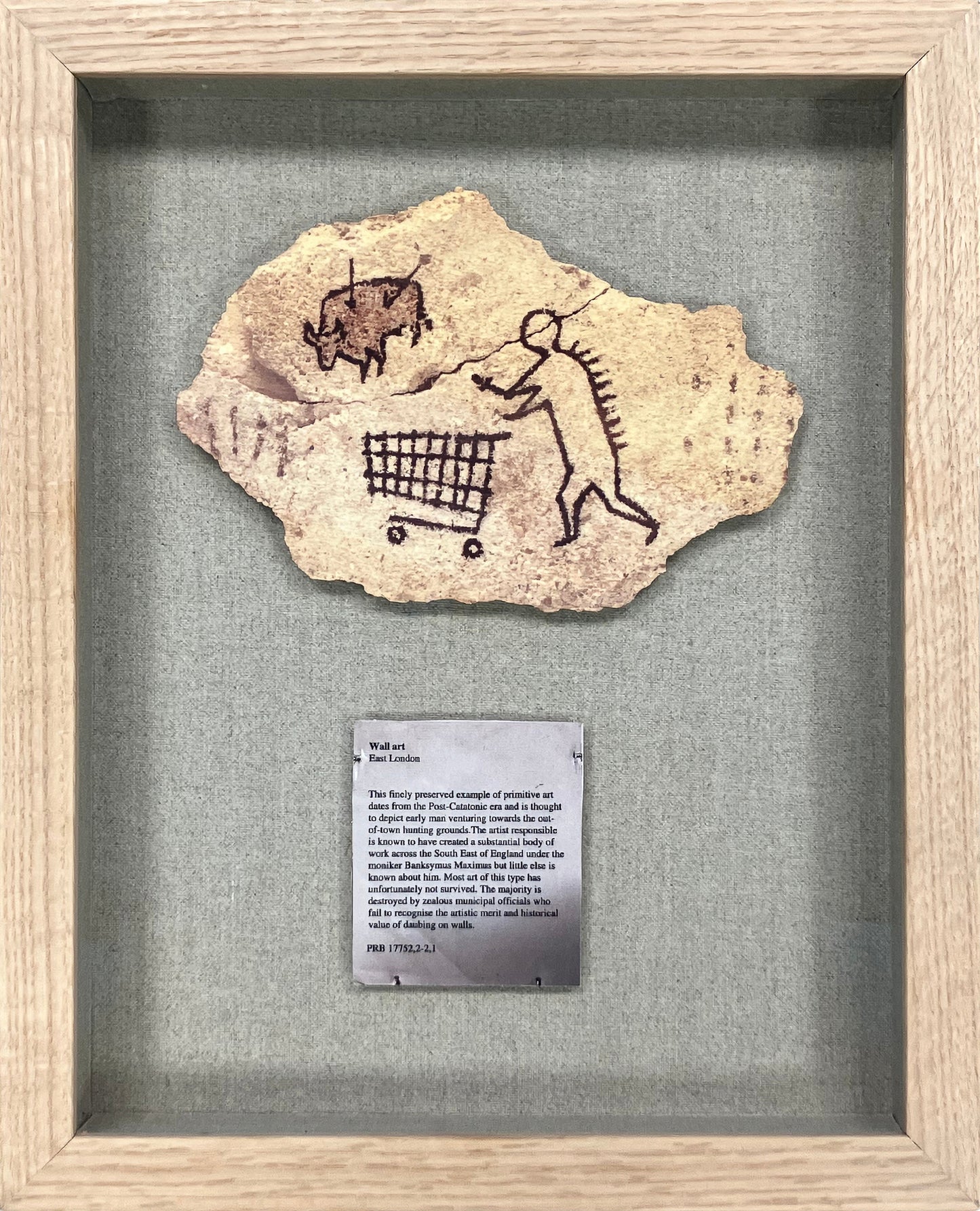 Banksy - 'Peckham Rock' - Official wooden postcard replica. A satirical cave-painting style illustration of a prehistoric man pushing a shopping trolley, originally placed as a hoax in the British Museum in 2005, now available at Creed Gallery Ascot.