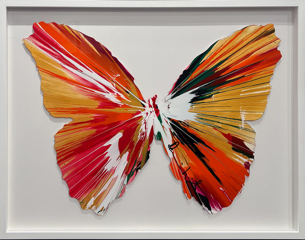 Damien Hirst butterfly-shaped spin painting in orange, red and gold, signed and framed in white, at Creed Gallery, Ascot
