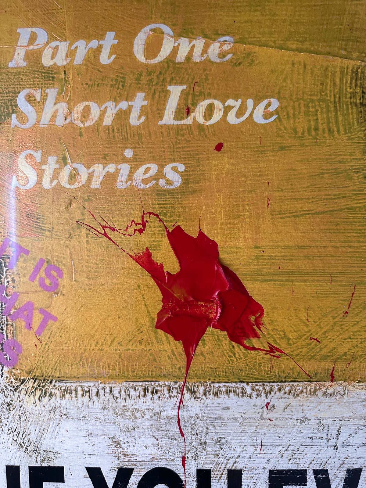 James McQueen 'If You Ever Leave Me' (Yellow) Hand-Painted Multiple, detail shot showing a hand-applied red paint splatter over aged 'Part One: Short Love Stories' book-cover text. Available at Creed Gallery, Ascot.