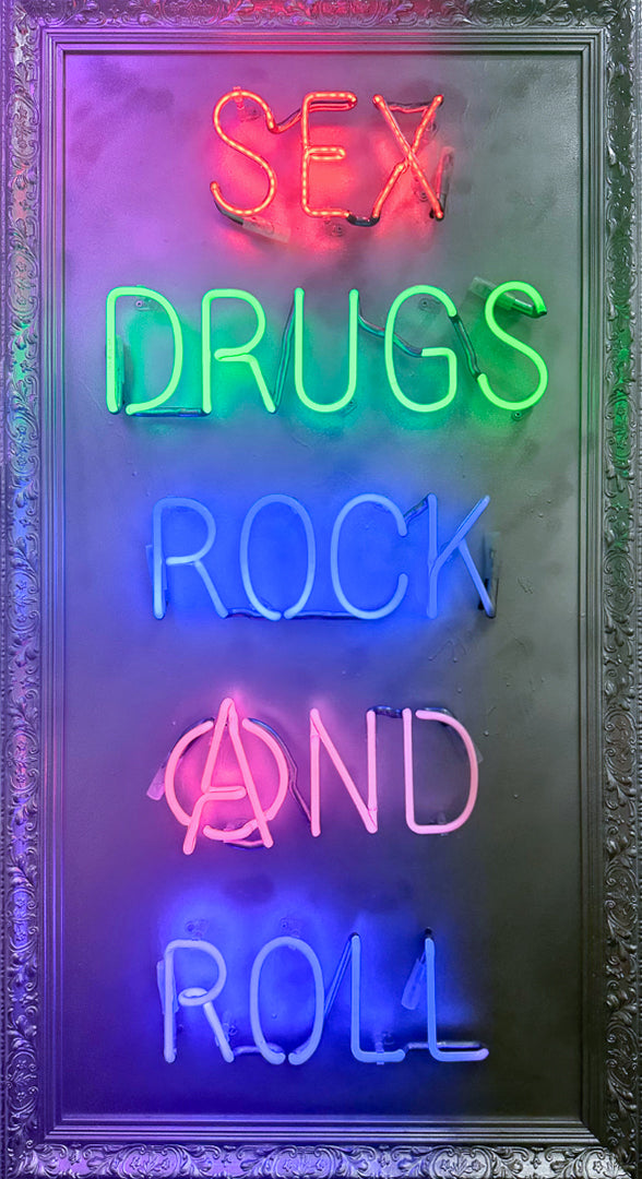 Mark Sloper "Sex, Drugs, Rock and Roll" hand-blown neon sign lit up in vibrant multi-colours on a hand-sprayed panel. A bold punk-inspired statement piece by Illuminati Neon, available at Creed Gallery Ascot.