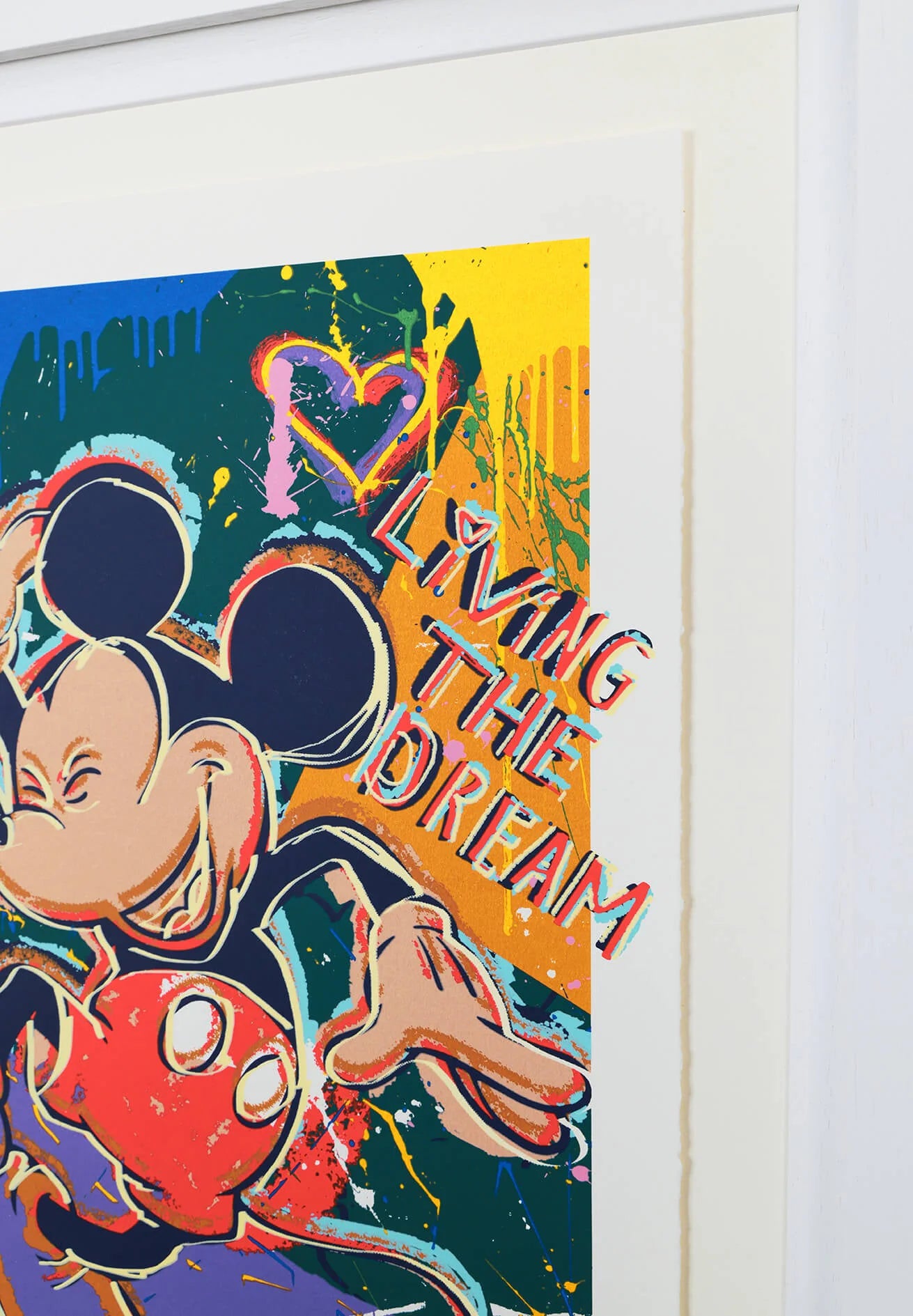 Close-up detail of the "Living the Dream" artwork showing the "Living the Dream" typography and expressive graffiti textures. The shot focuses on the high-quality finish of the fine art paper and the clean edge of the white contemporary frame.