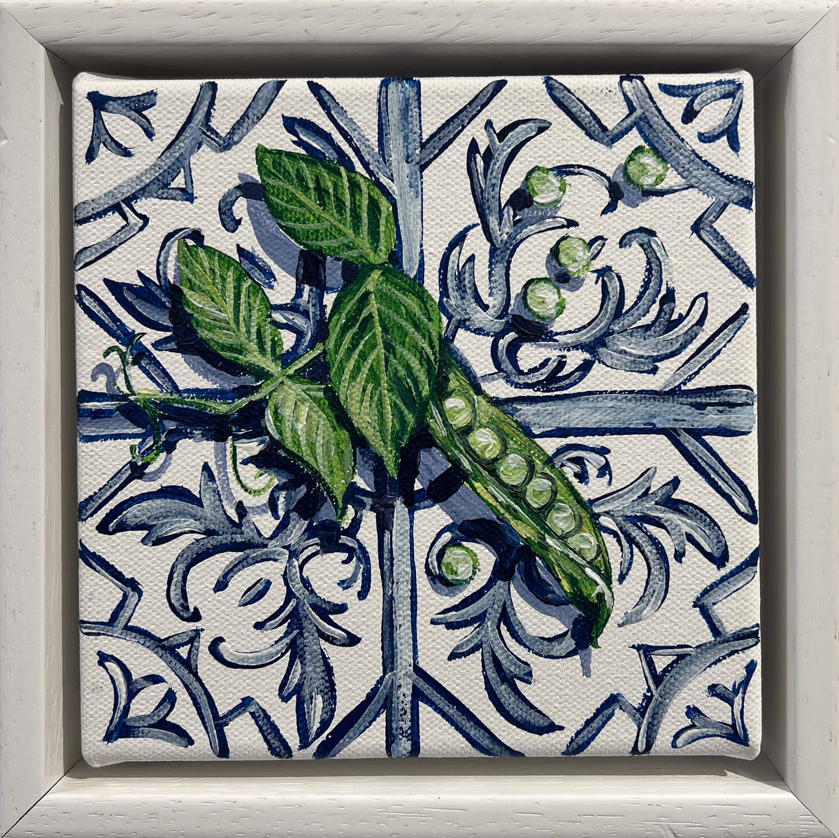 Painted still life of an open pea pod and green leaves on a blue and white Mediterranean tile, in a white frame