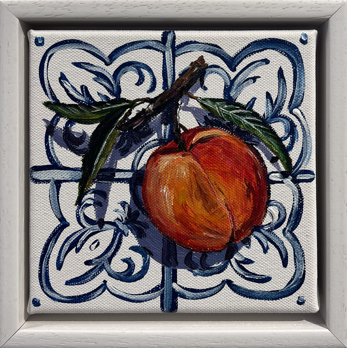 Painted still life of a ripe peach on a leafy twig on a blue and white Mediterranean tile, in a white frame