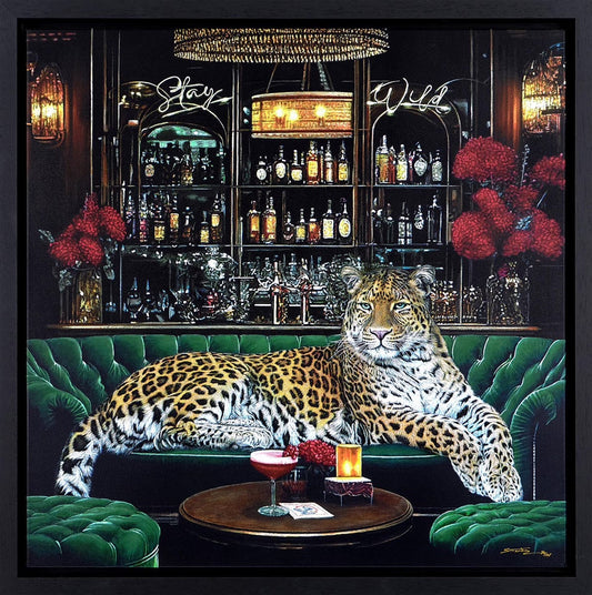 Steve Tandy Stay Wild, a leopard reclining on an emerald-green sofa among glassware and bottles.